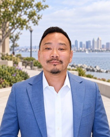 Dr. Charles Lu standing along the San Diego waterfront with the downtown skyline behind him