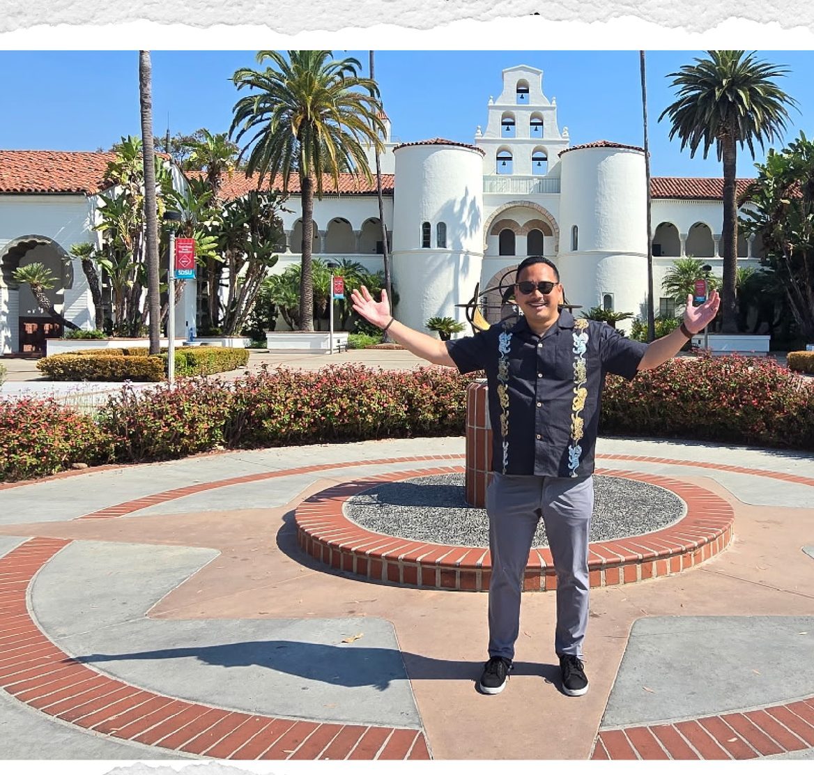 Dr. Charles Lu standing with open arms in front of Hepner Hall at San Diego State University